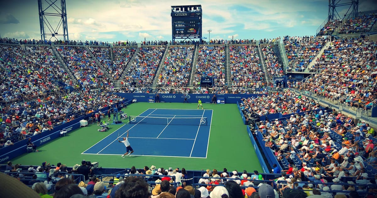 Spectators enjoying a tennis match from stadium seats representing inclusive participation