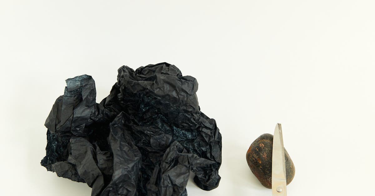 Artistic still life of rock, paper, and scissors on a white surface