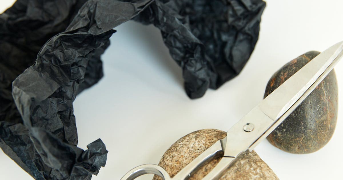 Scissors resting on top of smooth stones representing game variations